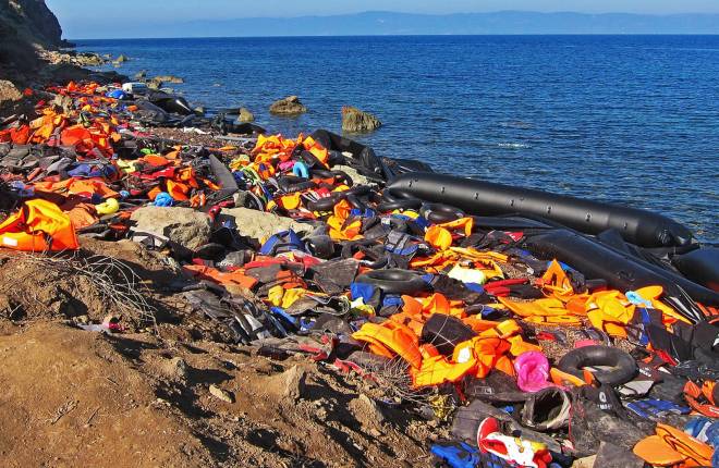 Discarded lifejackets on a beach with upturned small boat
